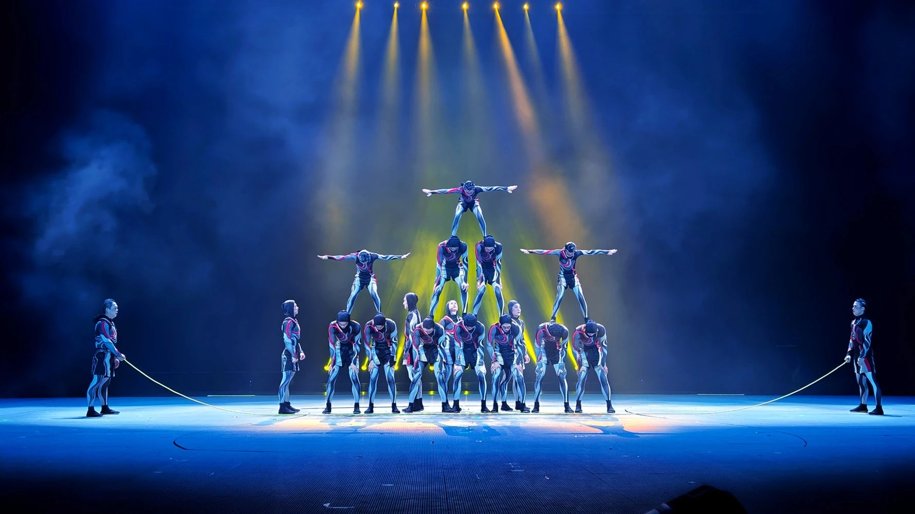 Odyssée — les acrobates du numéro des cordes sous les lumières de scène